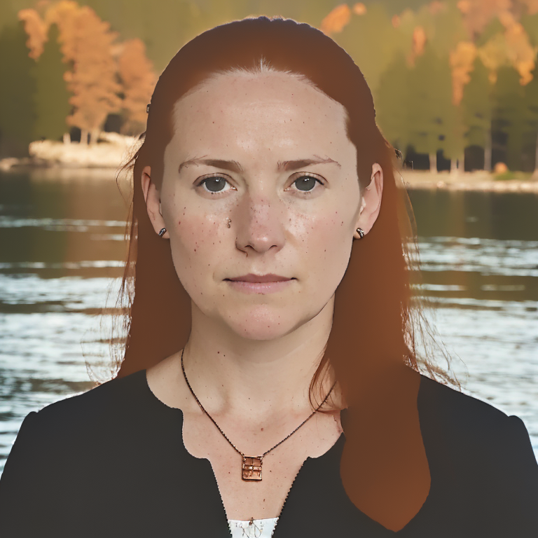 A person with red hair and a necklace in front of water